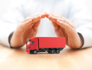 Hands covering a red truck symbolizing the coverage provided by truck insurance.
